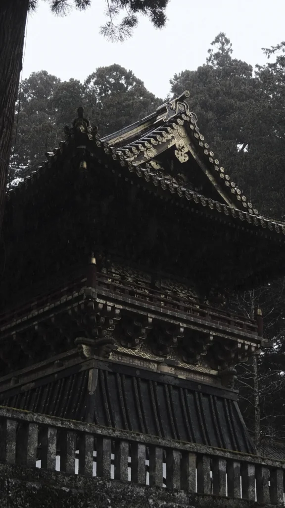 Bâtiment sombre aux toits sculptés du sanctuaire Tōshō-gū au milieu des cèdres, Nikkō
