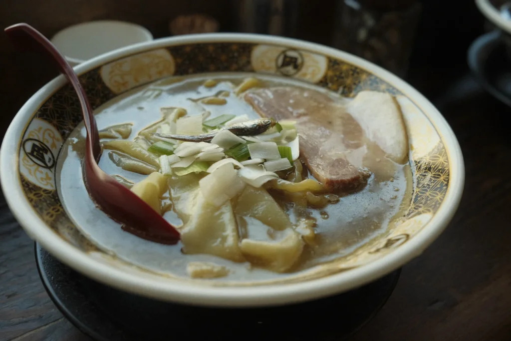 Bol de ramen fumant garni de nori, d'œuf et de porc, servi dans un restaurant de Tokyo
