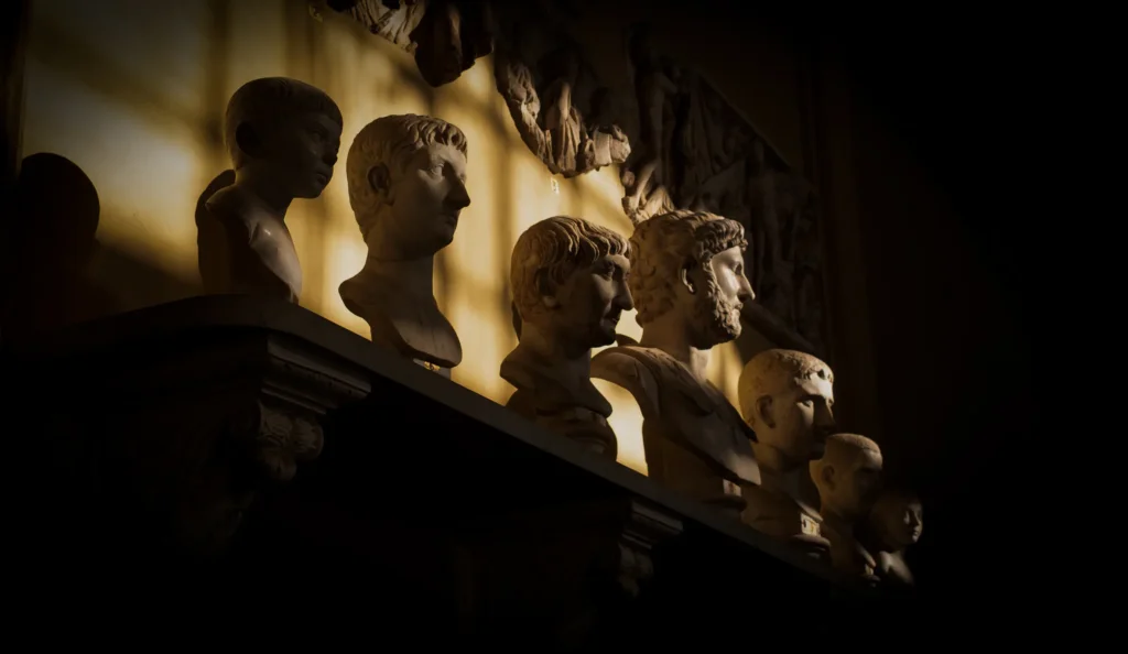 Série de bustes romains en marbre alignés sur une étagère, éclairés en lumière rasante dans une galerie des Musées du Vatican