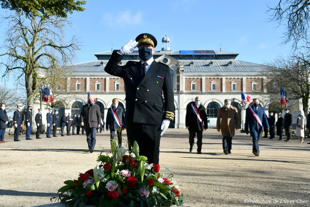 Préfet du Loir-et-Cher saluant devant une gerbe de fleurs lors d'une cérémonie officielle sur la place de la Halle aux Grains à Blois