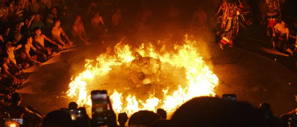 Danseur au centre d'un cercle de feu entouré de spectateurs, danse Kecak traditionnelle, Uluwatu, Bali