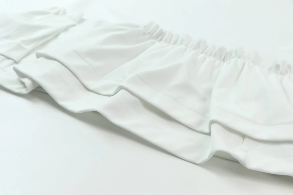 Gros plan sur l'ourlet d'une jupe blanche à volants superposés signée Comme des Garçons, coutures visibles