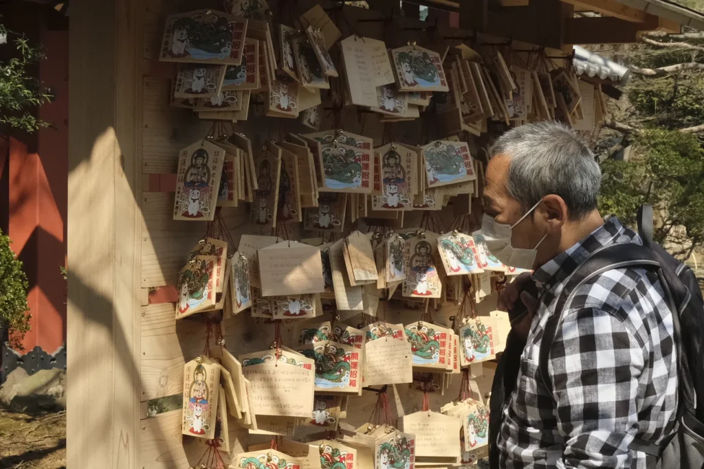 Plaquettes de bois ema accrochées au temple Gōtoku-ji, un homme masqué passe devant, Setagaya, Tokyo