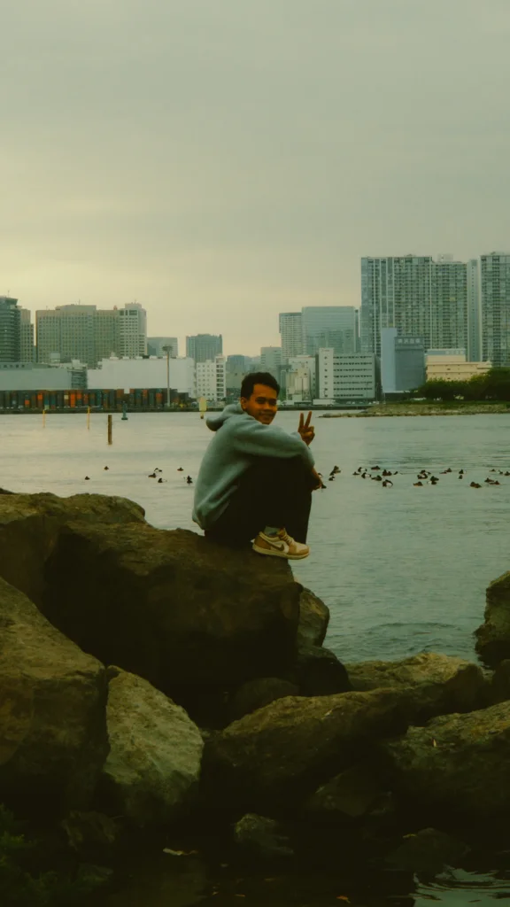 Homme assis sur des rochers face à l'eau, Odaiba, Tokyo