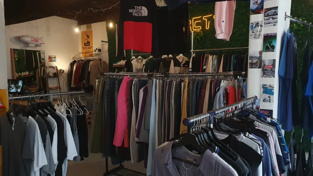 Intérieur de la friperie Egretta à Blois, portants de vêtements streetwear et vintage, néon et mur végétal