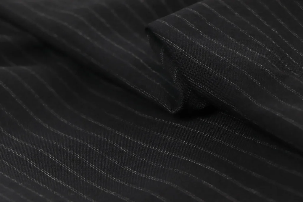 Macro photographie d'un tissu noir à fines rayures craie, plié en studio pour un shooting mode