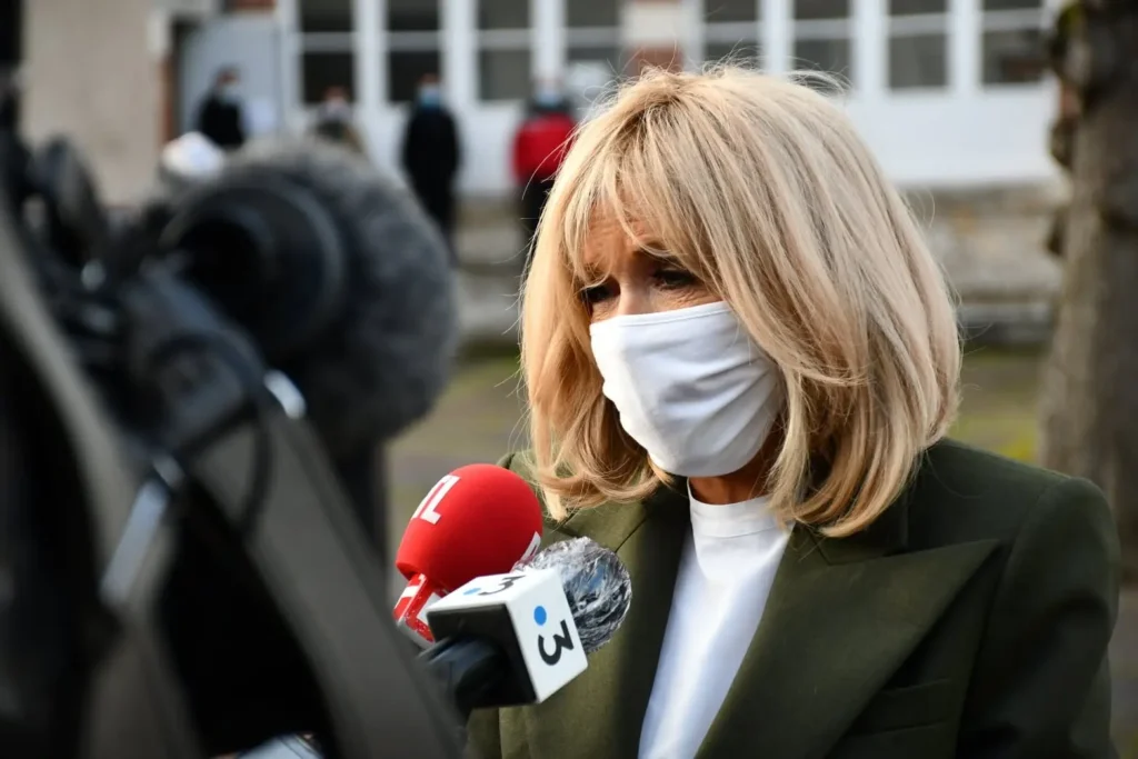 Femme interviewée face à plusieurs micros de radio et télévision lors d'une visite dans le cadre de l'opération Pièces Jaunes