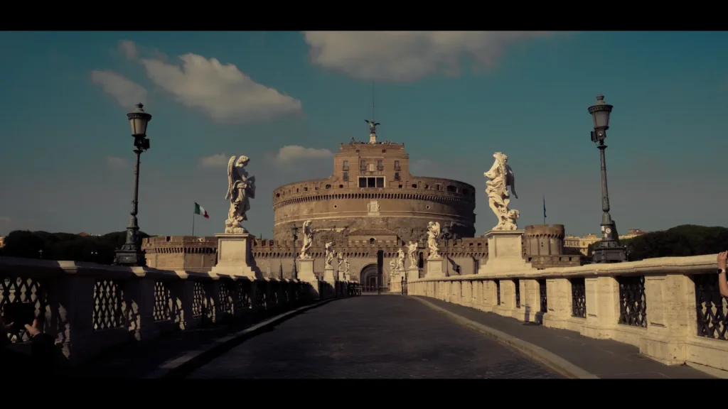 Vue du Château Saint-Ange depuis le Ponte Sant'Angelo, bordé de statues d'anges baroques, sous un ciel bleu
