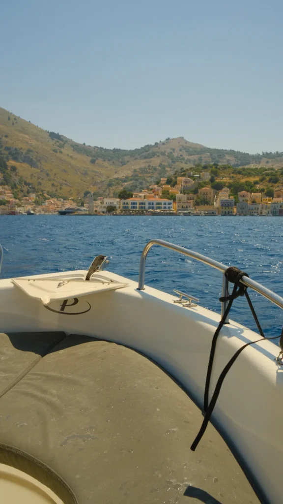 Proue d'un bateau pneumatique face à la baie de Saint Georges et au village coloré de Symi