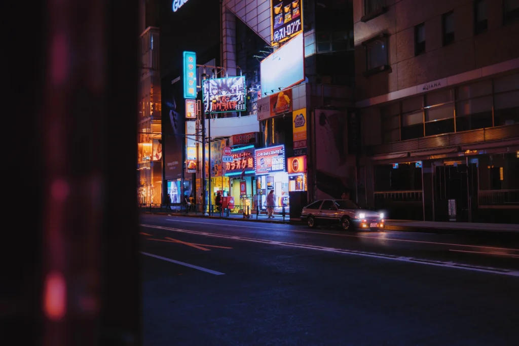 Rue de nuit éclairée de néons avec une voiture, Tokyo