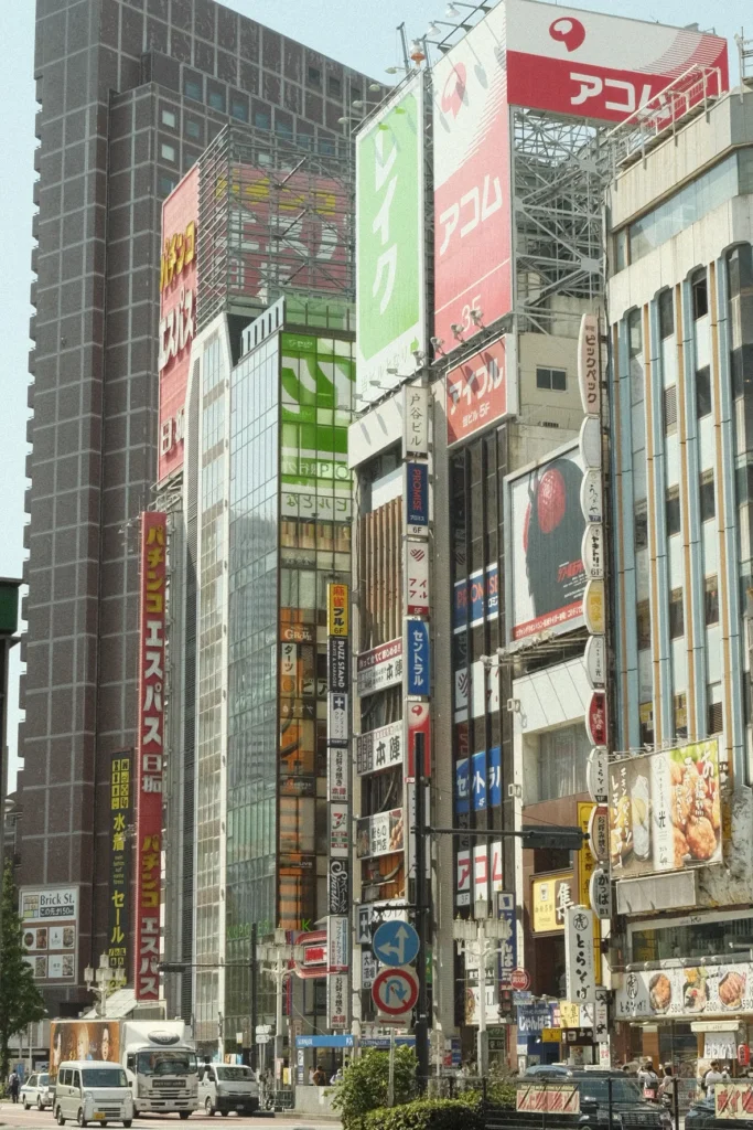 Rue de Shinjuku bordée de tours et d'enseignes verticales colorées dont l'enseigne Acom, Tokyo