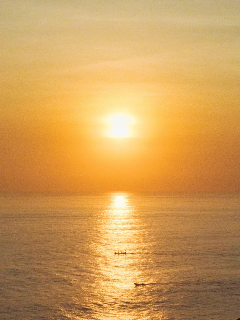 Reflet doré du soleil sur l'océan avec deux petites embarcations de pêcheurs, Uluwatu, Bali