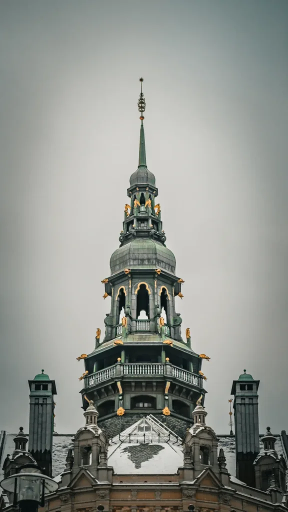 Vue frontale de la flèche du Stadshuset de Stockholm, couronnée des Trois Couronnes dorées, sous un ciel gris hivernal