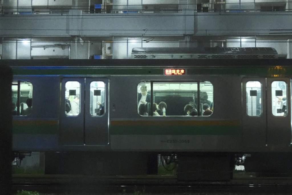 Train de banlieue à bande verte en gare la nuit, Tokyo