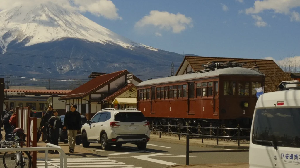 Vieux tramway marron garé près d'une gare avec le mont Fuji enneigé en arrière-plan, Kawaguchiko