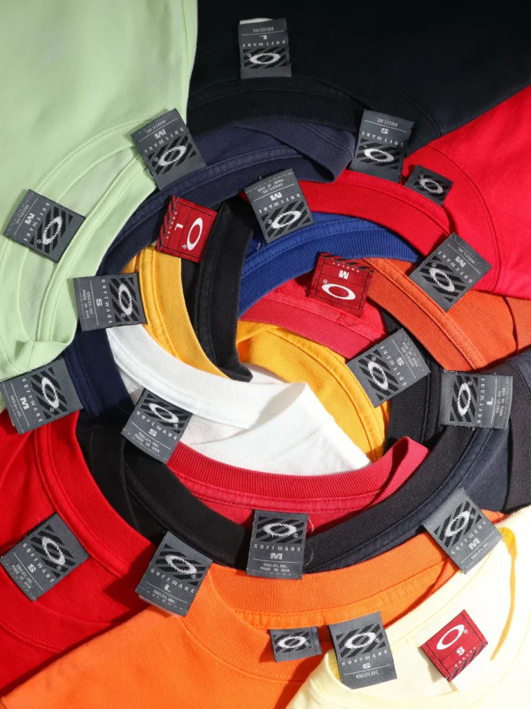 Pile de t-shirts Oakley vintage colorés disposés en spirale, étiquettes visibles, stock Egretta